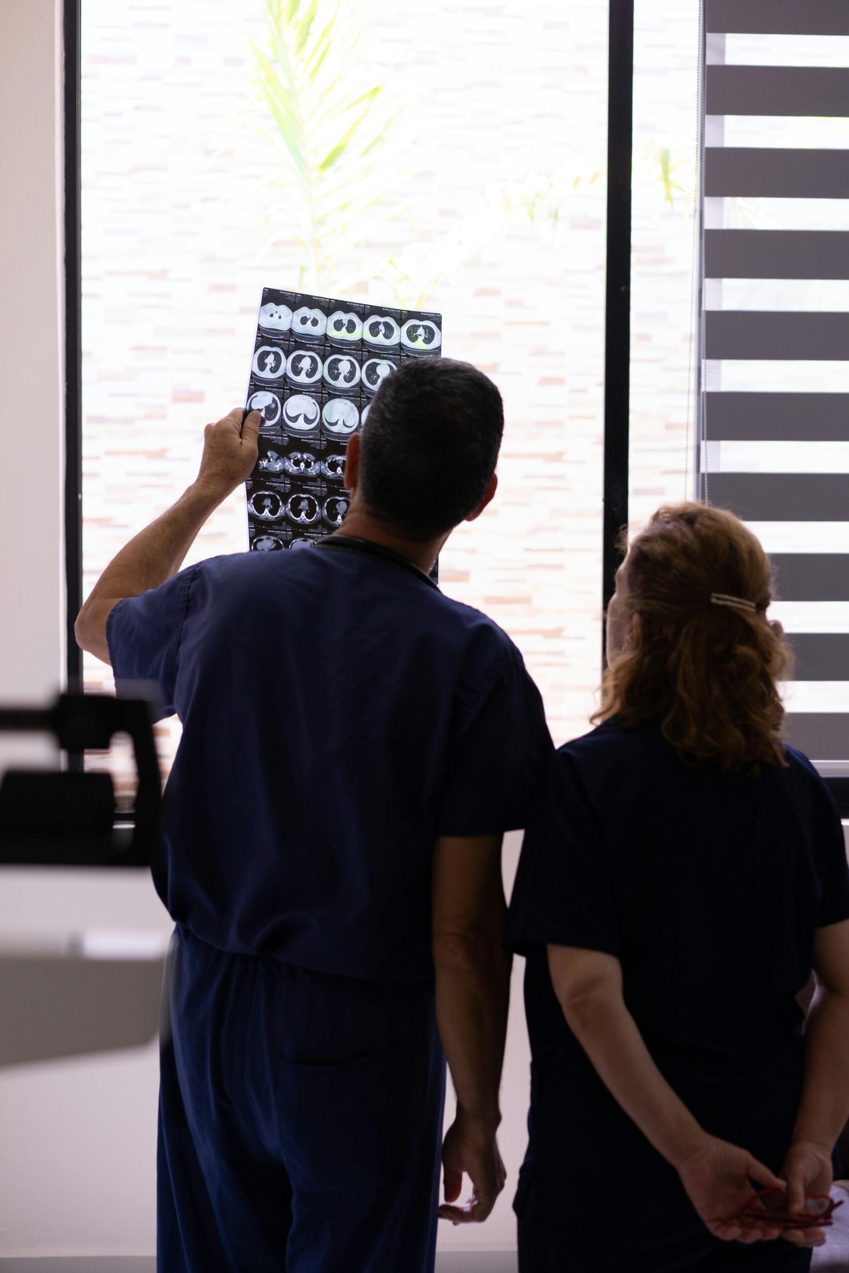Medical professionals examining an X-ray for diagnosis in a hospital environment.